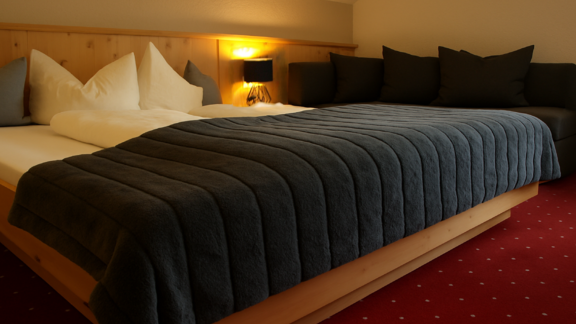 Ein gemütliches Schlafzimmer mit einem großen Bett und einer Couch. Die warmen Farben und die weichen Kissen sorgen für eine entspannte Atmosphäre. - Ferienhaus Schrankogelblick - Längenfeld