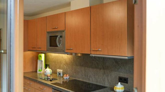 A modern kitchen with wooden cabinets and a stone countertop. It is well-lit and feels inviting. - Hauertalerhof - Längenfeld