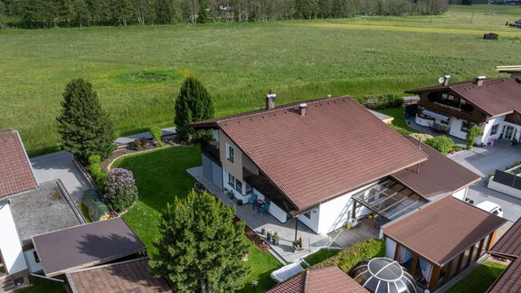 A quiet residential area with modern houses and well-kept gardens. In the background, a green meadow and wooded mountains extend. - Haus Klaudia Gstrein - Längenfeld
