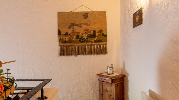 An inviting hallway with a wooden ceiling and a patterned wall decoration. On the left side, there is a wooden cabinet and a warm carpet on the floor. - Haus Klaudia Gstrein - Längenfeld