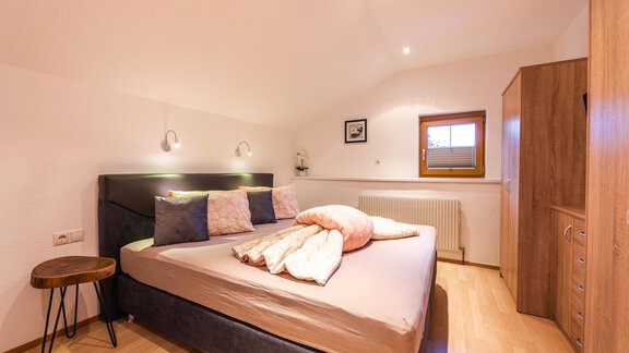 A modern bedroom with a large bed and cozy pillows. The room has hardwood floors and pleasant lighting. - Haus Viktoria - Längenfeld