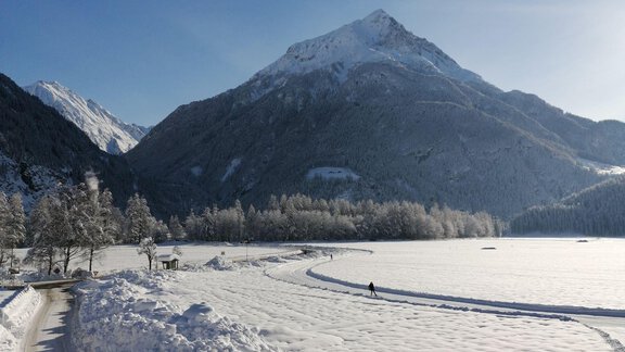A snowy landscape with mountains in the background. The sky is clear and blue. - Haus Viktoria - Längenfeld