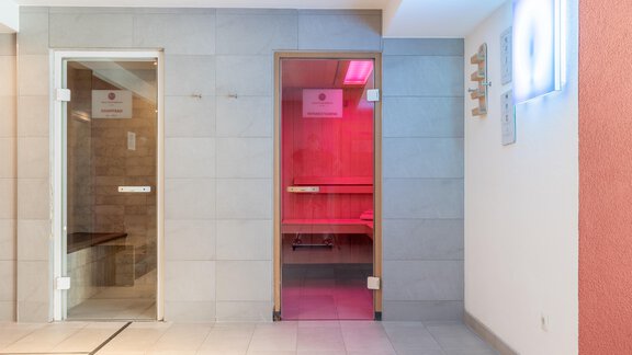 Ein moderner Wellnessbereich mit einem Sauna- und Dampfsaunaraum. Die Wände sind in neutralen Farben gehalten und es gibt sanfte Beleuchtung. - Hotel  Bergwelt - Längenfeld