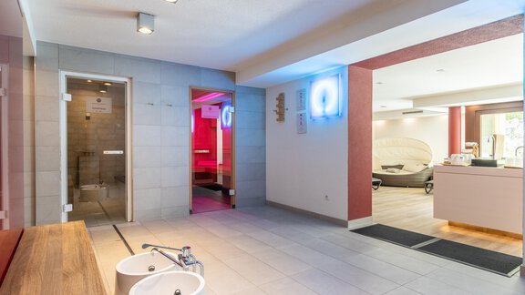 Ein moderner Wellnessbereich mit entspannender Atmosphäre. Im Hintergrund sind eine Sauna und Massagebetten zu sehen. - Hotel  Bergwelt - Längenfeld