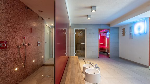 Ein moderner Wellnessbereich mit Duschen und sanftem Licht. Die Wände sind in neutralen Farben gehalten, und es gibt Platz für Entspannung. - Hotel  Bergwelt - Längenfeld