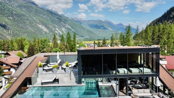 Eine moderne Immobilie mit einem Infinity-Pool auf dem Dach. Die umliegenden Berge und Wälder bieten eine atemberaubende Aussicht. - Hotel Stern - Längenfeld