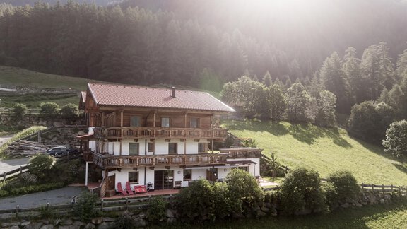 Ein gemütliches alpenländisches Haus umgeben von grünen Wiesen und Bäumen. Im Hintergrund sind Berge und ein sonniger Himmel zu sehen. - MYALPS Himmelreich - Längenfeld
