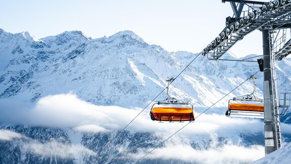 Eine Seilbahn fährt über schneebedeckte Berge. Der Himmel ist klar und die Landschaft wirkt winterlich und majestätisch. - MYALPS Jordans Lodge - Längenfeld