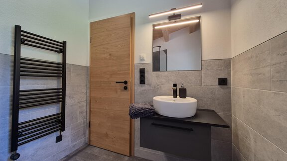 Ein modernes Badezimmer mit einer eleganten Dusche und einem Waschbecken. Die Wände sind in neutralen Tönen gehalten und es gibt einen Handtuchhalter aus Metall. - Apart Alpenflair - Niederthai