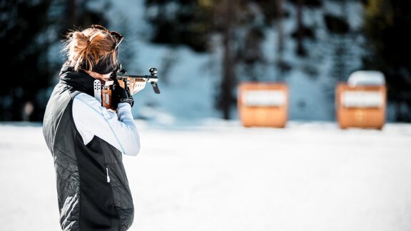 A person is shooting with a rifle in a snow-covered landscape. In the background, two orange targets can be seen. - Apart Alpenflair - Niederthai