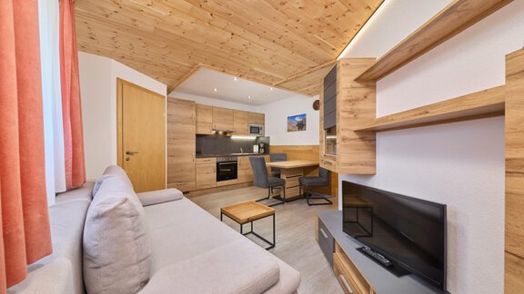 A modern apartment with a cozy seating area and an open kitchen. Bright wood decor and large windows create an inviting atmosphere. - Appartement Lea - Niederthai