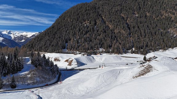 Eine schneebedeckte Landschaft mit hohen Bergen und dichten Wälder. Die Sonne scheint und der Himmel ist klar. - Gipfelblick Appartements - Niederthai