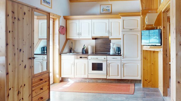 Eine moderne Küche mit weißen Schränken und Holzdetails. Sie ist hell und gut ausgestattet, ideal für das Kochen. - Gipfelblick Appartements - Niederthai