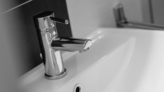 Ein modernes Waschbecken mit einem glänzenden Wasserhahn. Im Hintergrund ist ein Handtuch sichtbar. - Sonnenhof - Niederthai