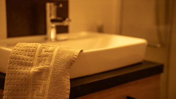 Ein modernes Badezimmer mit einem eleganten Waschbecken und einem handtuch. Das Ambiente ist warm und einladend. - Sonnenhof - Niederthai