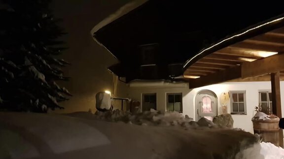 A cozy house in the snow at night. The entrance is illuminated and there are high snow drifts visible. - Appartementhaus Schalfblick - Obergurgl 