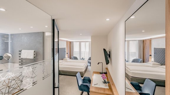 A modern hotel room with two beds and a desk. Generous windows provide plenty of light and an elegant atmosphere. - Austria Gourmet & Wine Hotel - Obergurgl 