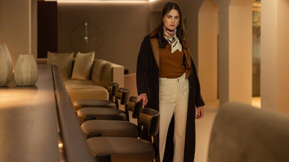 A stylishly dressed woman stands in a modern interior. The room has warm lighting and elegant furniture. - Austria Gourmet & Wine Hotel - Obergurgl 