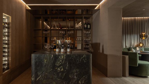 An elegant bar with a marble counter and a selection of drinks. The atmosphere is modern and stylish, with soft lighting. - Austria Gourmet & Wine Hotel - Obergurgl 