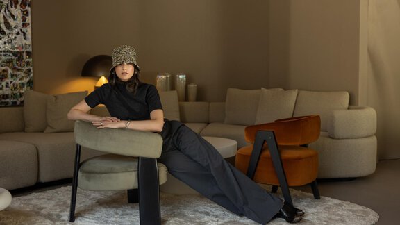 A stylish woman sits relaxed in a modern room. The room is furnished with elegant furniture and soft color tones. - Austria Gourmet & Wine Hotel - Obergurgl 