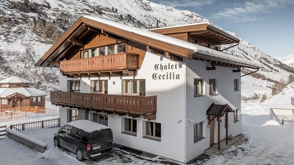 A charming chalet in the snow with a large balcony and rustic wood details. In the foreground is a black car. - Chalet Cecilia by MYALPS - Obergurgl 