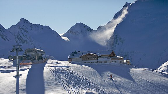A snowy mountain landscape with a cozy ski chalet. In the background, majestic mountains and a clear sky can be seen. - Ferienwohnung Poschacherhof - Obergurgl 