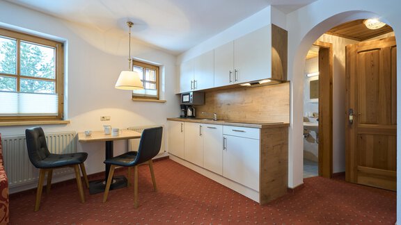A modern kitchen with a table and chairs. The room has bright walls and a cozy atmosphere. - Forest Chalet - Obergurgl 