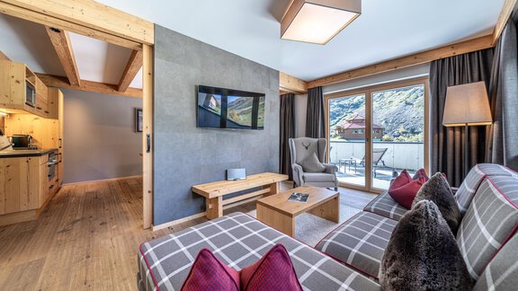 A modern living room with a cozy seating area and large window. The space is bright and inviting, featuring stylish furniture and wood details. - Gletscherblick - Serviced Apartments - Obergurgl 