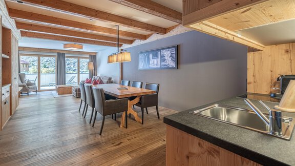 A modern living and dining room with a wooden beam ceiling. The room is cozily furnished and has access to a terrace. - Gletscherblick - Serviced Apartments - Obergurgl 
