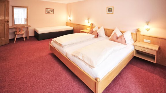 A cozy room with two beds and a table. The walls are in soft colors and the floor is covered with red carpet. - Haus Timmelseck - Obergurgl 
