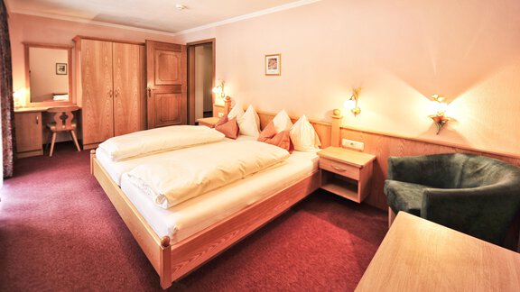 A cozy bedroom with two beds and wooden furniture. The room has a warm tone and is well lit. - Haus Timmelseck - Obergurgl 
