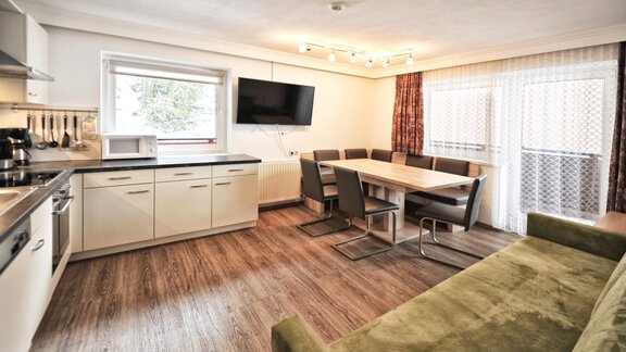 A modern apartment with an open kitchen and a dining area. Large windows provide plenty of light and a cozy atmosphere. - Haus Timmelseck - Obergurgl 