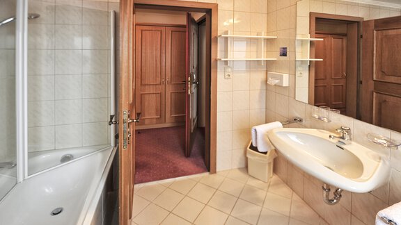 A modern bathroom with a bathtub and a shower. The walls are tiled and the fittings are simple and functional. - Haus Timmelseck - Obergurgl 