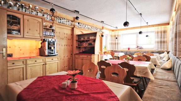 A cozy restaurant with wooden furniture and tables set in red. The warm colors create an inviting atmosphere. - Haus Timmelseck - Obergurgl 