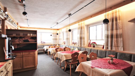 A cozy dining room with wooden chairs and tables. Large windows let in plenty of light and the room's design is friendly and inviting. - Haus Timmelseck - Obergurgl 