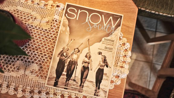A magazine titled "Snow Society" is lying on a table. It features four women posing on the beach in waterproof outfits. - Haus Timmelseck - Obergurgl 