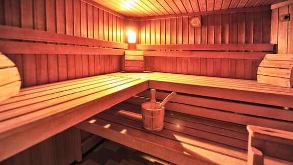 A wooden sauna with benches and a bucket for pouring. Soft light creates a relaxing atmosphere. - Haus Timmelseck - Obergurgl 