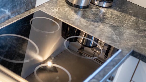 A modern kitchen countertop with a smooth cooking surface and modern kitchen appliances. The surface reflects light and exhibits an elegant design. - Haus Timmelseck - Obergurgl 