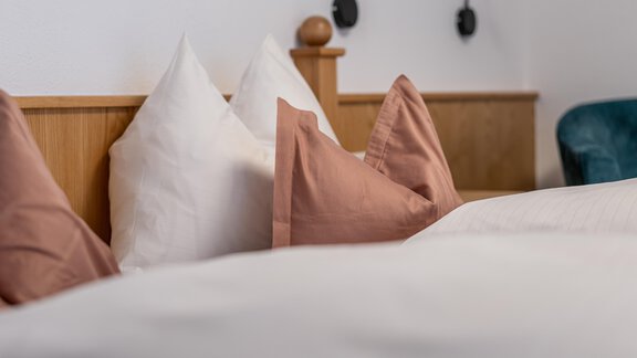 A cozy bedroom with white and pink pillows. The headboard of the bed is made of light wood. - Haus Timmelseck - Obergurgl 