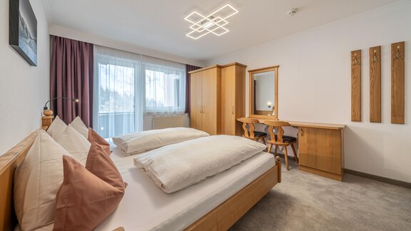 A modern room with two beds and an elegant lighting design. The room is friendly and bright with a large window and a wooden table. - Haus Timmelseck - Obergurgl 