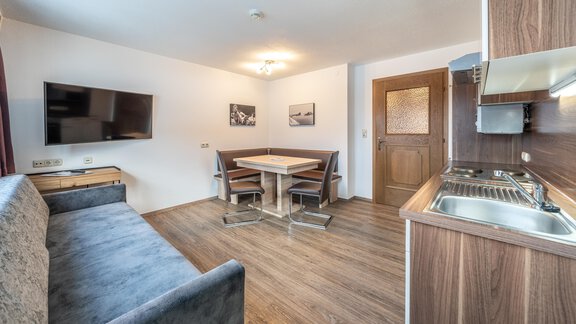A modern living room with a cozy sofa and a dining area. The open kitchen is well-equipped, and the room is bright and inviting. - Haus Timmelseck - Obergurgl 