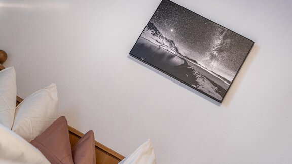 A black and white photo of a nighttime landscape hangs on the wall. In the foreground, soft cushions in various colors are visible. - Haus Timmelseck - Obergurgl 
