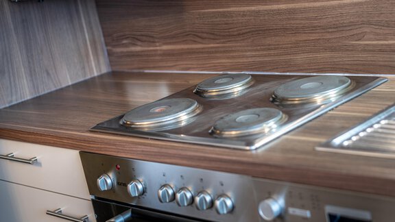A modern kitchen with a cooktop and an oven. The wood surface gives the room a warm atmosphere. - Haus Timmelseck - Obergurgl 