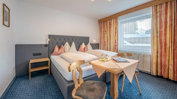 A cozy bedroom with a large bed and two chairs. A table is set for two people and the window lets in a lot of light. - Haus Timmelseck - Obergurgl 