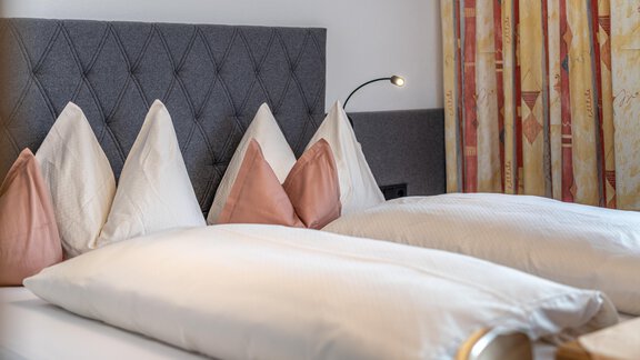 A cozy bedroom with two beds and elegant pillows. The soft lighting and warm colors create a relaxed atmosphere. - Haus Timmelseck - Obergurgl 