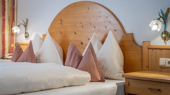 A cozy bedroom with a large double bed and striking pillows. On the wall, there are appealing light sources and a wooden desk. - Haus Timmelseck - Obergurgl 