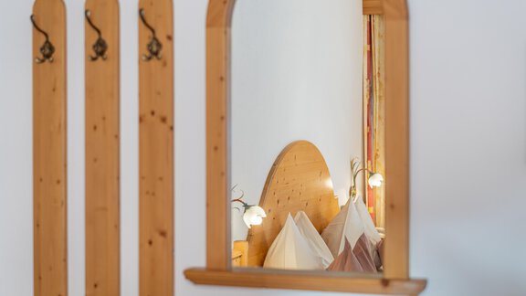 A cozy bedroom with a wooden headboard and soft lighting elements. The mirror reflects the warm atmosphere of the room. - Haus Timmelseck - Obergurgl 