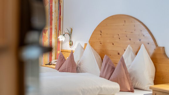 A cozy bedroom with a wooden bed and soft pillows. Gentle colors and a warm atmosphere invite you to relax. - Haus Timmelseck - Obergurgl 