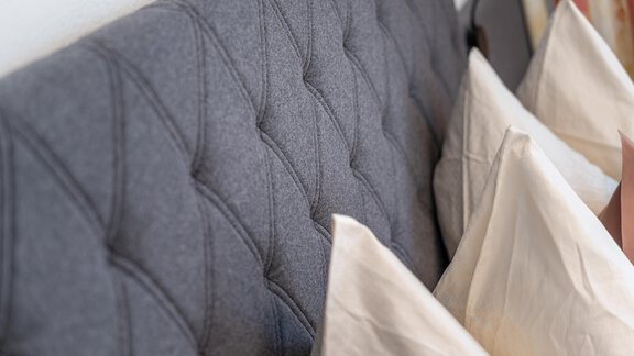 A cozy headboard made of gray fabric with an elegant pattern. Below are several white pillows. - Haus Timmelseck - Obergurgl 