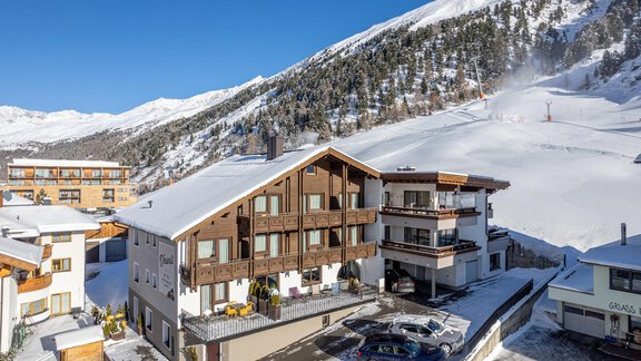 A cozy building in the Alps, surrounded by snow-covered mountains. The sky is clear and the landscape is wintery beautiful. - Haus Verwall Appartements - Obergurgl 